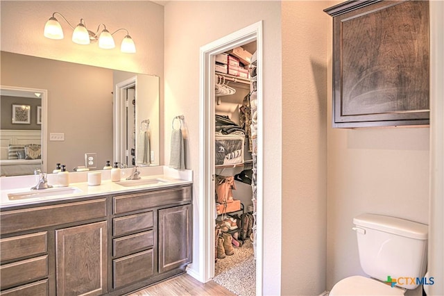 full bath featuring double vanity, wood finished floors, toilet, and a sink