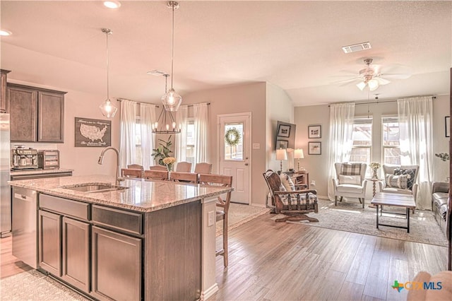 kitchen with appliances with stainless steel finishes, a kitchen breakfast bar, light wood-type flooring, and a sink