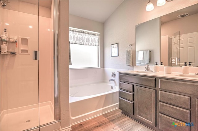 full bath featuring visible vents, a stall shower, wood finished floors, a bath, and a sink