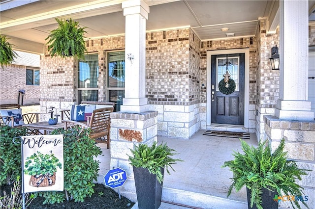 doorway to property with an outdoor living space, brick siding, and covered porch