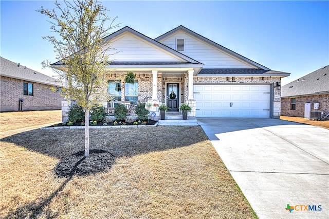 view of front of home with central air condition unit, covered porch, concrete driveway, a front yard, and a garage