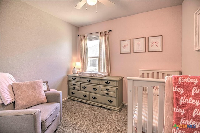 bedroom featuring a crib, carpet, and ceiling fan