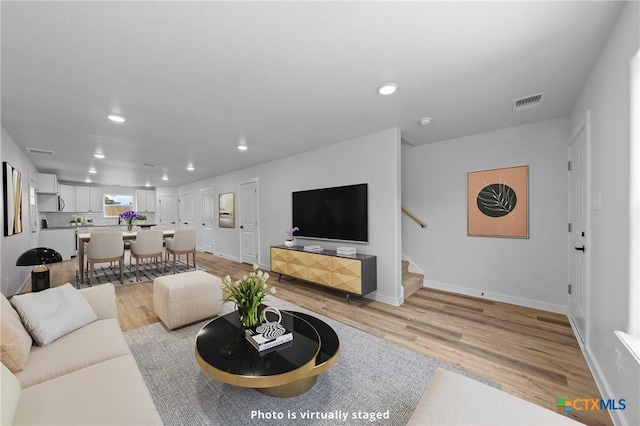 living room featuring light wood-style floors, stairway, and recessed lighting