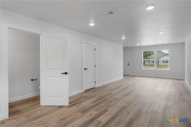 unfurnished room featuring baseboards, visible vents, and wood finished floors