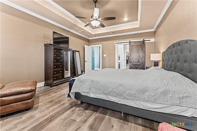 bedroom with ceiling fan, a barn door, a raised ceiling, and crown molding