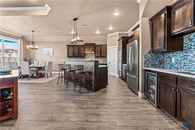 kitchen featuring a center island, wine cooler, stainless steel refrigerator with ice dispenser, pendant lighting, and a breakfast bar