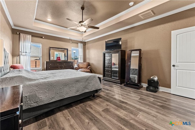 bedroom featuring a textured ceiling, a raised ceiling, ceiling fan, crown molding, and hardwood / wood-style floors