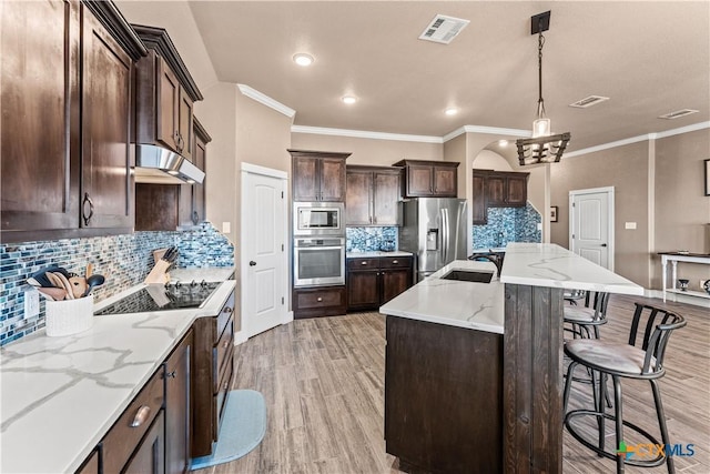 kitchen with sink, hanging light fixtures, stainless steel appliances, tasteful backsplash, and a kitchen island with sink