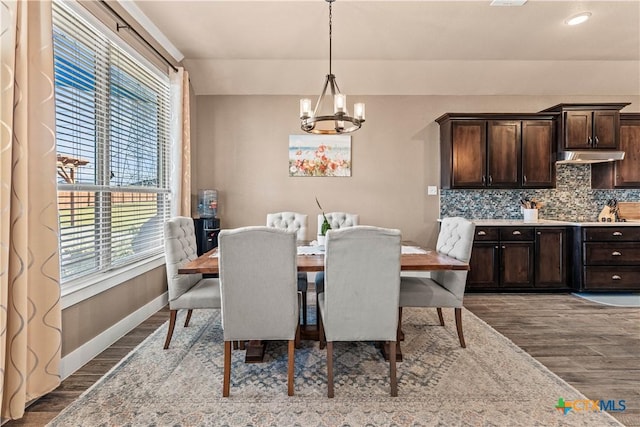 dining area with hardwood / wood-style flooring and an inviting chandelier