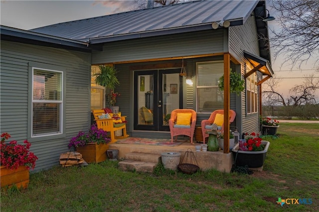 exterior space featuring a lawn, french doors, metal roof, and a standing seam roof