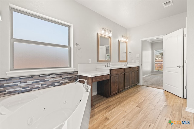 bathroom with vanity, hardwood / wood-style flooring, a tub to relax in, and a healthy amount of sunlight