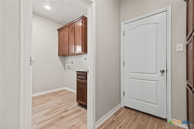 clothes washing area with hookup for an electric dryer, light hardwood / wood-style floors, washer hookup, and cabinets