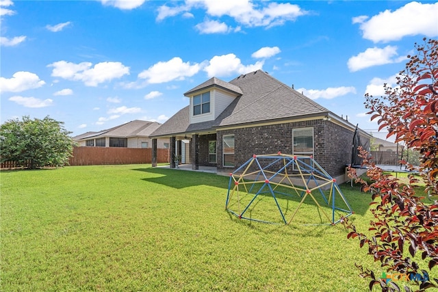 rear view of house featuring a yard, a trampoline, and a patio area