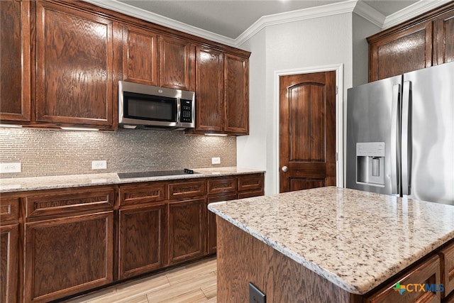 kitchen with appliances with stainless steel finishes, a center island, and light stone countertops