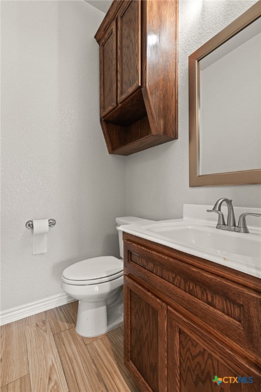 bathroom with wood-type flooring, vanity, and toilet