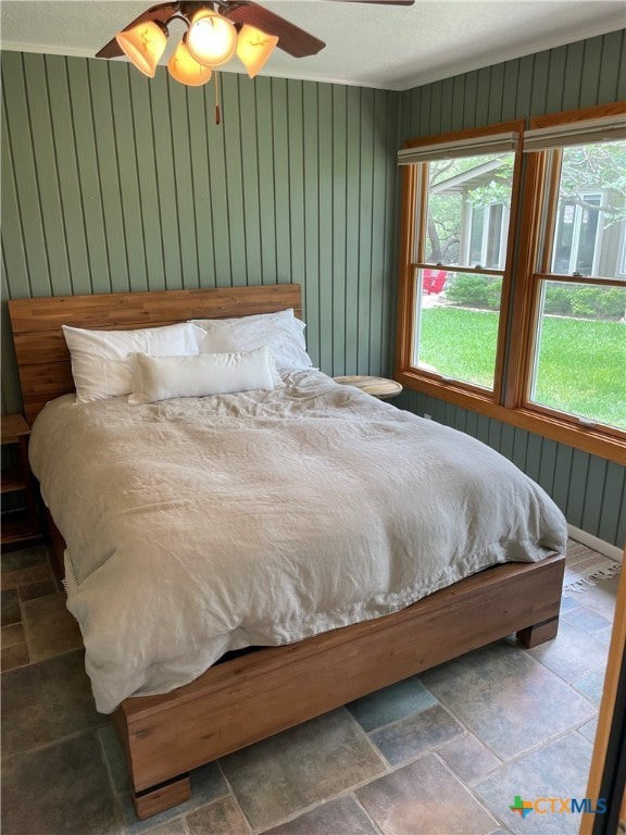 bedroom with wood walls and ceiling fan