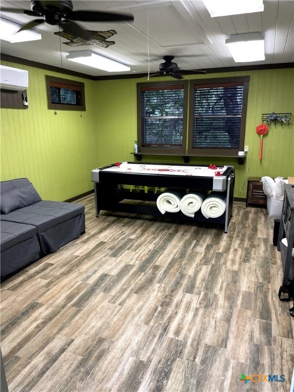 playroom with wood walls, hardwood / wood-style flooring, ceiling fan, and a wall mounted air conditioner