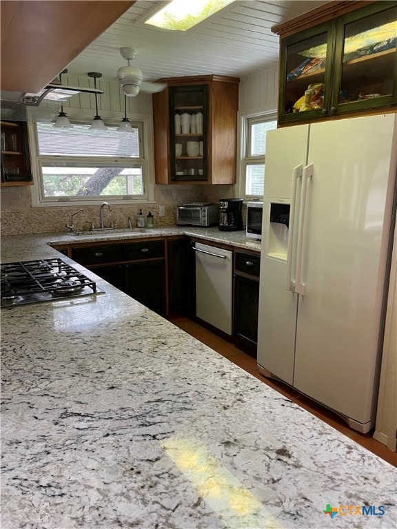 kitchen featuring stainless steel appliances, sink, light stone counters, tasteful backsplash, and ceiling fan