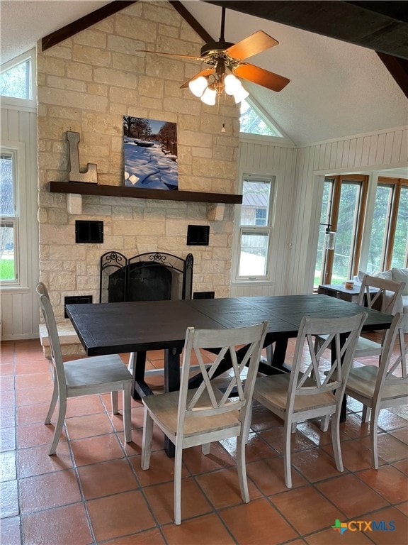 tiled dining space featuring a fireplace, a wealth of natural light, ceiling fan, and lofted ceiling with beams