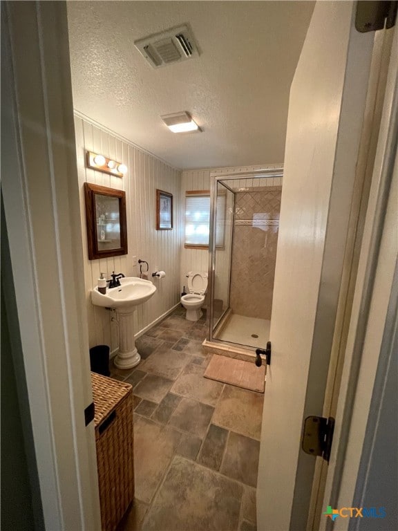 bathroom featuring toilet, an enclosed shower, a textured ceiling, and ornamental molding