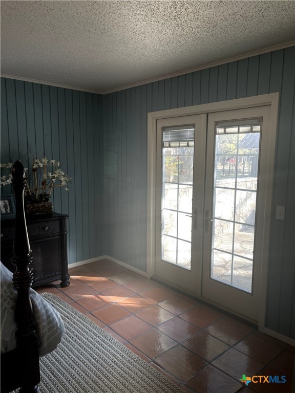 doorway to outside featuring wooden walls, french doors, and a textured ceiling