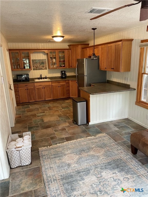 kitchen with ceiling fan, a textured ceiling, and decorative light fixtures