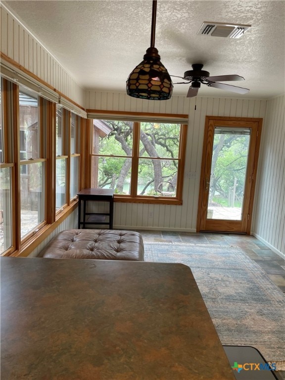 unfurnished sunroom with ceiling fan