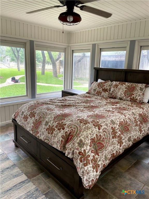 bedroom with wood walls, wooden ceiling, and ceiling fan