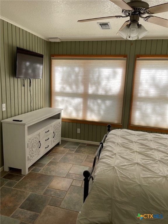 unfurnished bedroom featuring a textured ceiling, wood walls, and ceiling fan