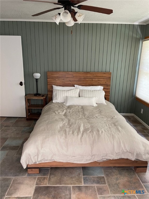 bedroom with a textured ceiling, wood walls, and ceiling fan