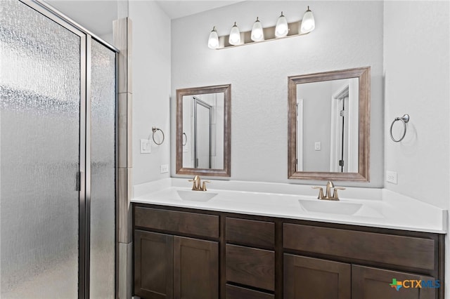 bathroom featuring a shower with shower door and vanity