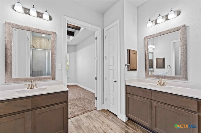 bathroom with wood-type flooring, vanity, and a shower with door