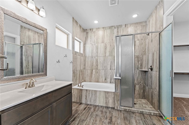 bathroom featuring wood-type flooring, independent shower and bath, and vanity