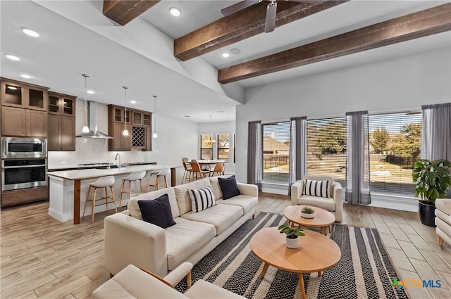 living room with light wood-type flooring, a wealth of natural light, and beam ceiling