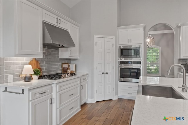 kitchen featuring a sink, light countertops, stainless steel appliances, and under cabinet range hood