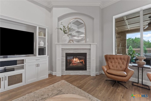 living area with light wood-type flooring, ornamental molding, baseboards, and a glass covered fireplace