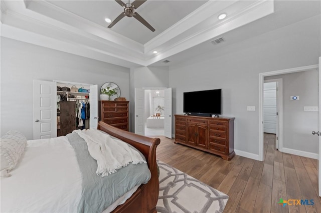bedroom with visible vents, recessed lighting, a raised ceiling, and wood finished floors