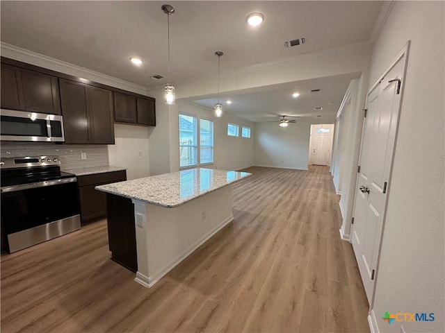 kitchen with ceiling fan, light stone countertops, dark brown cabinets, a kitchen island, and appliances with stainless steel finishes