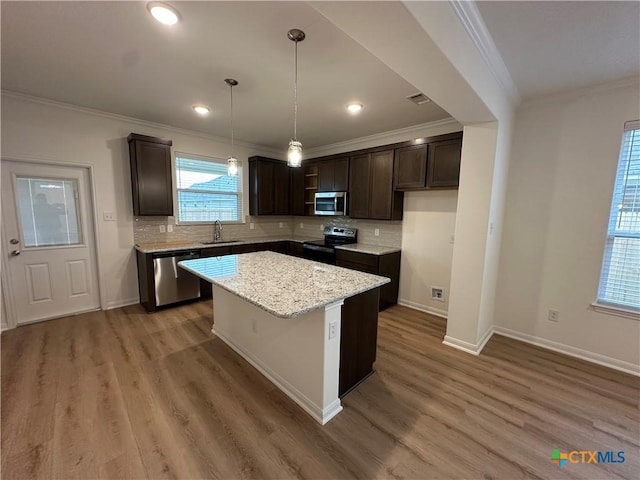 kitchen with a center island, sink, stainless steel appliances, light stone counters, and hardwood / wood-style flooring