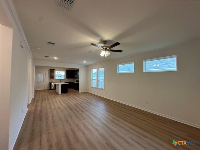 unfurnished living room with ceiling fan, wood-type flooring, and crown molding