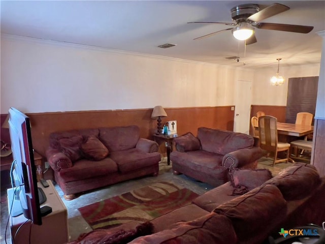 living room with carpet flooring, ceiling fan with notable chandelier, and crown molding