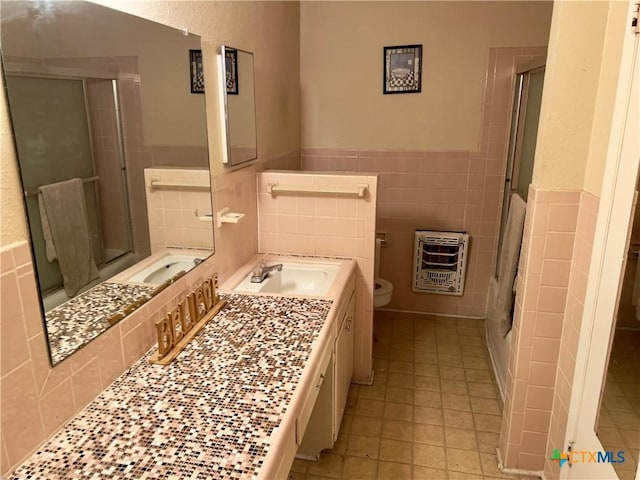 bathroom featuring vanity, toilet, tile walls, an enclosed shower, and heating unit