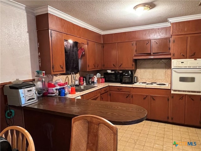 kitchen featuring backsplash, a textured ceiling, white appliances, crown molding, and sink