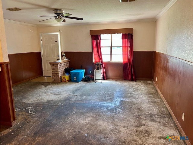 1504 E Central Ave, Temple, TX 76501 - unfurnished room featuring visible vents, ceiling fan, crown molding, wainscoting, and wood walls
