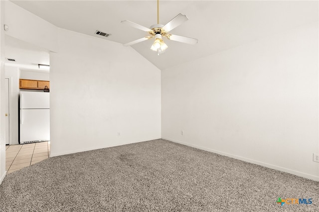 spare room featuring ceiling fan, light carpet, and vaulted ceiling