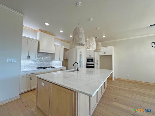 kitchen with white cabinetry, appliances with stainless steel finishes, decorative light fixtures, and a spacious island