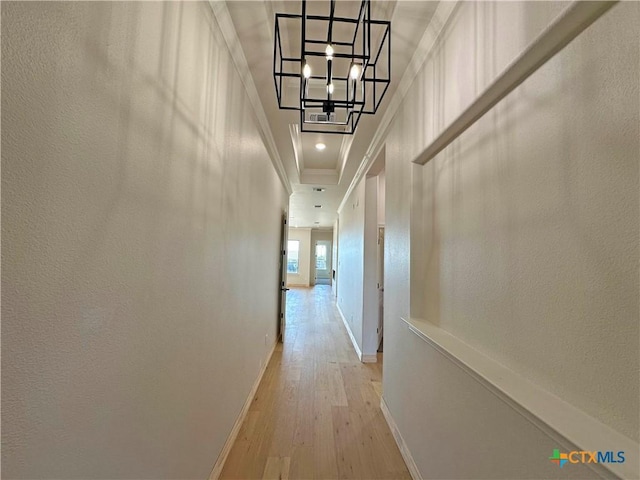 hallway with ornamental molding, light hardwood / wood-style flooring, and a notable chandelier