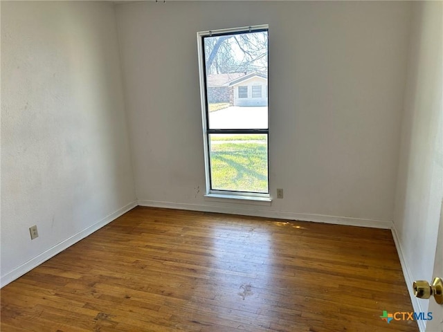 spare room with baseboards and wood finished floors