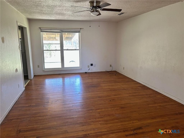 unfurnished room with ceiling fan, wood finished floors, visible vents, and a textured ceiling