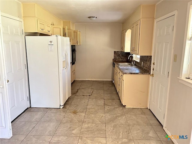 kitchen with oven, a sink, dark countertops, white fridge with ice dispenser, and light tile patterned floors